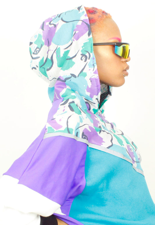 side view of hoodie which has purple and green patterned hood with purple, turquoise and white colour block sweater